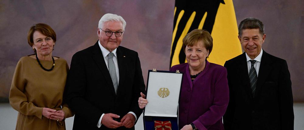 Frank-Walter Steinmeier überreicht Angela Merkel den Orden. Daneben stehen ihr Ehemann Joachim Sauer (rechts) und Steinmeiers Ehefrau Elke Büdenbender (links).