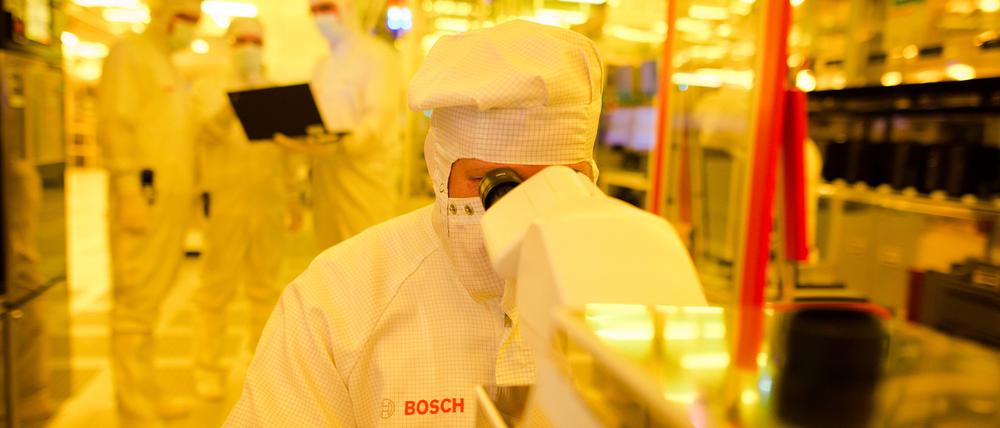 ARCHIV - Ein Mitarbeiter von Bosch kontrolliert am 16.06.2017 in einem Gelbraum eines Wafer fabs (Halbleiterwerk) in Reutlingen (Baden-Württemberg) eine Halbleiterscheibe mit einem Mikroskop auf mögliche Fehler. (zu dpa «Bosch baut Chipfabrik in Sachsen für eine Milliarde Euro» vom 19.06.2017) Foto: Christoph Schmidt/dpa +++(c) dpa - Bildfunk+++