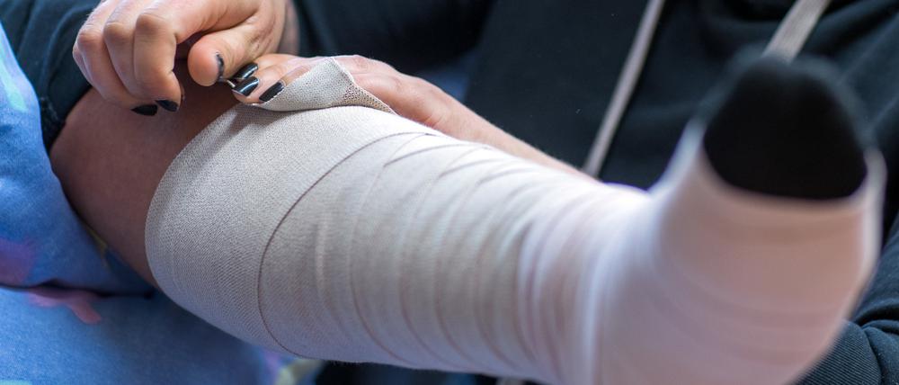 Eine Pflegeschülerin legt bei einer Mitschülerin, die eine zu pflegende Person spielt einen Thrombose-Verband an.