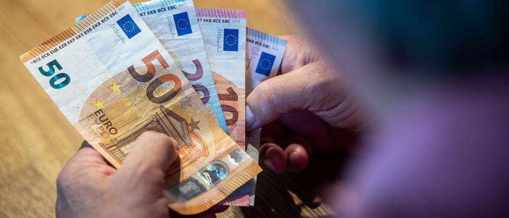 Ein älterer Mann sitzt an einem Tisch und zählt Geld.