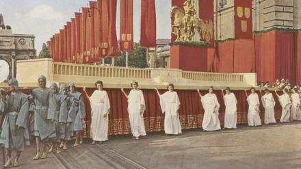 In München fand 1937 der „Festzug 2000 Jahre Deutsche Kultur“ statt. Im Hintergrund: das Großmodell der „Zeppelinfeld“-Tribüne auf dem Nürnberger Reichsparteitagsgebände.