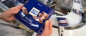 Eine Mitarbeiterin des Schokoladenherstellers Ritter Sport prüft die Verpackung einer Tafel Schokolade. 