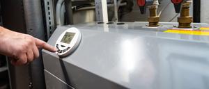 Ein Mann bedient eine Luftwärmepumpe, die im Keller eines Wohnhauses steht.