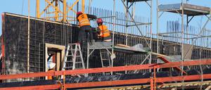 Drei Männer arbeiten auf einer Etage eines Rohbaus für Wohn- und Geschäftshäuser.