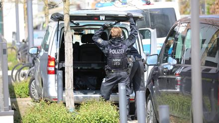 Ein Polizist steht nach einer Großrazzia gegen einen Anbieter von Sportwetten an einem Auto. 