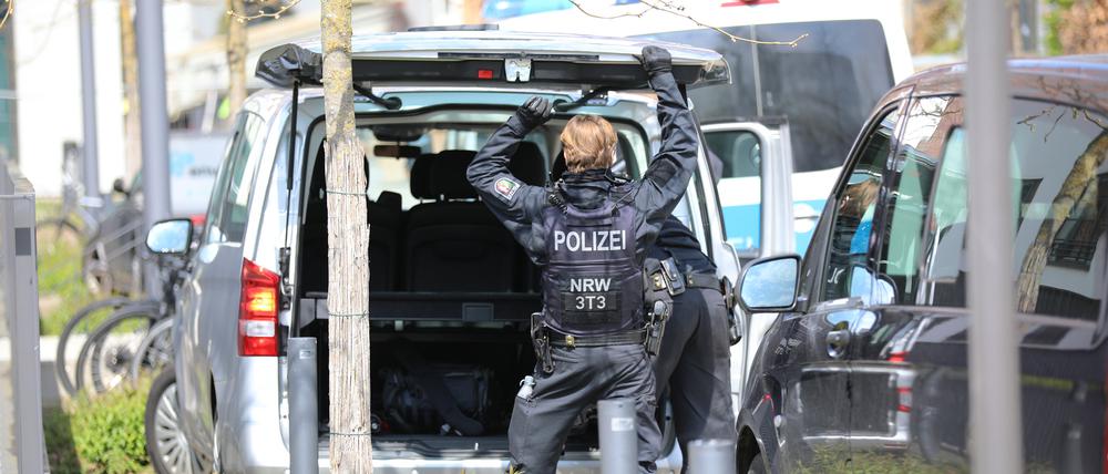 Ein Polizist steht nach einer Großrazzia gegen einen Anbieter von Sportwetten an einem Auto. 