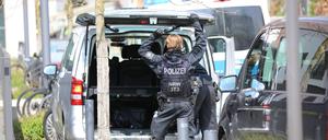 Ein Polizist steht nach einer Großrazzia gegen einen Anbieter von Sportwetten an einem Auto.