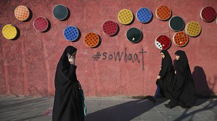 Mit Tschador und Hidschab gekleidete Frauen gehen an einer dekorierten Wand vorbei. Im Iran setzt die Polizei den Kopftuchzwang ab sofort mithilfe von Videoüberwachung durch.