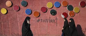 Mit Tschador und Hidschab gekleidete Frauen gehen an einer dekorierten Wand vorbei. Im Iran setzt die Polizei den Kopftuchzwang ab sofort mithilfe von Videoüberwachung durch.