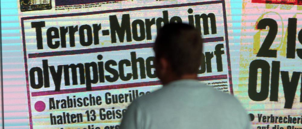 Ein Besucher betrachtet die Installation mit Titelseite und Schlagzeile der „AZ Abendzeitung“ über den Mordanschlag am Erinnerungsort an das Olympia-Attentat vom 05. September 1972.
