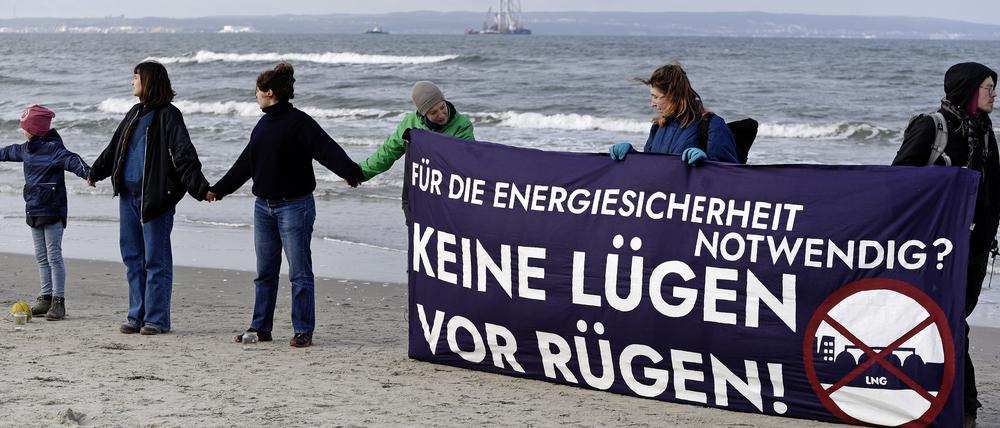 Mit einem Transparent und der Aufschrift „Für die Energiesicherheit notwendig? Keine Lügen vor Rügen“ stehen Menschen am Strand von Binz auf der Insel Rügen in einer Menschenkette als Protest gegen ein für die Insel vorgesehenes Flüssigerdgas-Terminal.  
