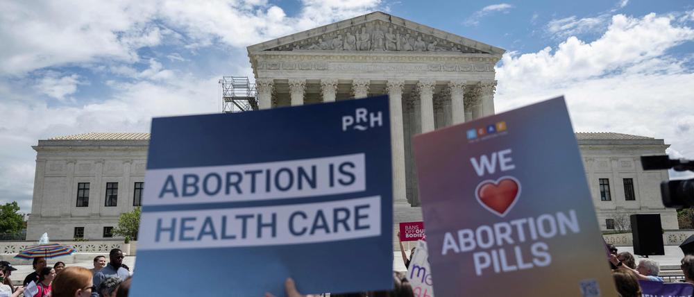 Demonstrierende halten vor dem Supreme Court Schilder in die Höhe. 
