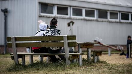 12.10.2021, Brandenburg, Eisenhüttenstadt: Zwei Asylsuchende in der Erstaufnahmeeinrichtung Eisenhüttenstadt sitzen auf einer Bank. In Brandenburg und Sachsen füllen sich die Aufnahmeeinrichtungen mit Menschen, die aus Irak, Syrien oder Afghanistan über Belarus, Polen und das Baltikum nach Deutschland kommen. Foto: Fabian Sommer/dpa +++ dpa-Bildfunk +++
