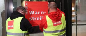 dpatopbilder - 24.04.2023, Berlin: Streikende befestigen ein Plakat mit der Aufschrift "Warnstreik" am Terminal des Flughafens BER. Seite heute Morgen 03:30 Uhr wird am Flughafen gestreikt. Alle abgehenden Flüge wurden gestrichen. Foto: Jörg Carstensen/dpa +++ dpa-Bildfunk +++