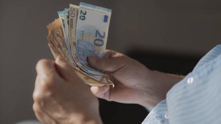 Ein Mann hält mehrere Euroscheine in der Hand.