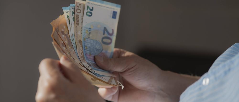 Ein Mann hält mehrere Euroscheine in der Hand.