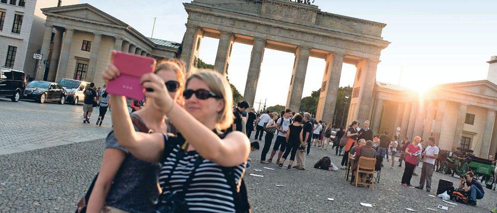 Zwei Touristinnen fotografieren sich am 20.08.2015 mit einem Smartphone im Abendlicht vor dem Brandenburger Tor in Berlin.