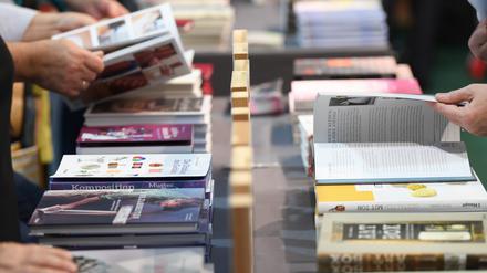 Besucher der Frankfurter Buchmesse blättern an einem Verlagsstand in Büchern.