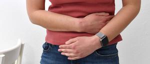 Eine junge Frau hält sich ihren Unterleib.