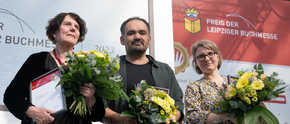 27.04.2023, Sachsen, Leipzig: Autorin Regina Scheer (v.l.), erhält den Preis der Leipziger Buchmesse in der Kategorie Sachbuch/Essayistik, Autor Dinçer Güçyeter, erhält den Preis der Leipziger Buchmesse in der Kategorie Belletristik, und Johanna Schwering, erhält den Preis der Leipziger Buchmesse in der Kategorie Übersetzung und stehen während der Verleihung des Leipziger Buchpreises 2023 in der Glashalle auf der Bühne. Der Preis der Leipziger Buchmesse wird in den drei Kategorien Belletristik, Sachbuch/Essayistik und Übersetzung vergeben und ist mit insgesamt 60 000 Euro dotiert. Foto: Hendrik Schmidt/dpa +++ dpa-Bildfunk ++