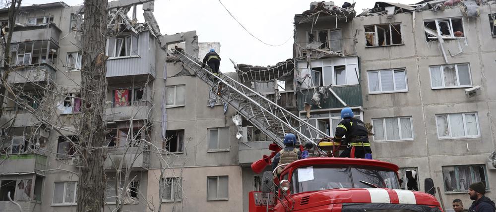 Feuerwehrleute arbeiten daran, ein Feuer zu löschen, während sie nach einem Raketenangriff nach möglichen Opfern suchen.