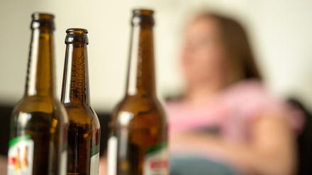 Eine Frau hinter leeren Bierflaschen.