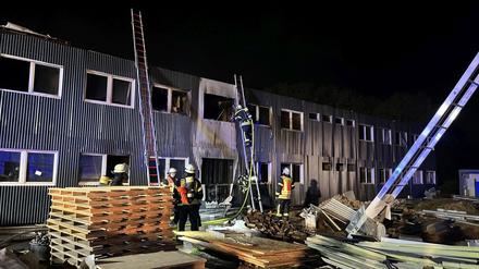 Feuerwehrleute löschen einen Brand in einer noch unbewohnten und für die Unterbringung von Flüchtlingen vorgesehenen Containeranlage.
