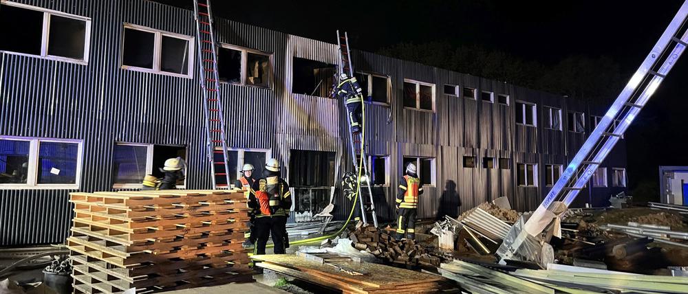 Feuerwehrleute löschen einen Brand in einer noch unbewohnten und für die Unterbringung von Flüchtlingen vorgesehenen Containeranlage.