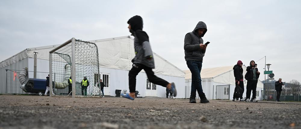 Flüchtlinge halten sich auf dem Gelände einer Flüchtlingsunterkunft vor den Zelten auf.