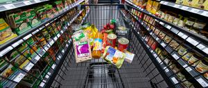 Verschiedene Lebensmittel liegen in einem Supermarkt in einem Einkaufswagen. 