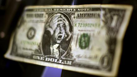 Eine Karikatur einer US-Dollar-Note mit dem Abbild George Washingtons, der sich die Hände über den Kopf zusammenschlägt, in der Börse in Frankfurt am Main an einem Monitor (Archivbild).