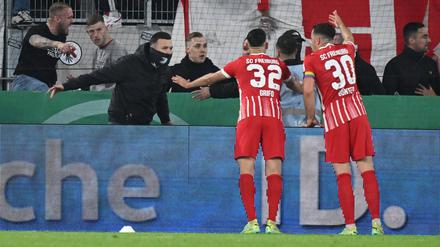 Freiburger Fans verschaffen sich nach dem Münzwurf Zugang zum Innenraum des Stadions. Freiburgs Vincenzo Grifo und Kapitän Christian Günter versuchen, zu beruhigen.