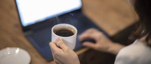 Eine Frau hält eine Kaffeetasse in ihrer Hand.