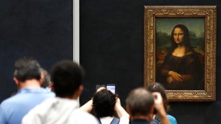 Besucher machen Fotos vor Leonardo da Vincis Meisterwerk „Mona Lisa“ im Louvre-Museum. 