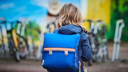Ein Schüler steht mit Schulranzen über den Schulhof einer Grundschule in Prenzlauer Berg.