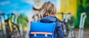 Ein Schüler steht mit Schulranzen über den Schulhof einer Grundschule in Prenzlauer Berg.