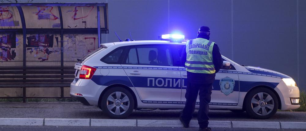 Ein serbischer Polizeibeamter steht vor einem Polizeiauto (Symbolbild).