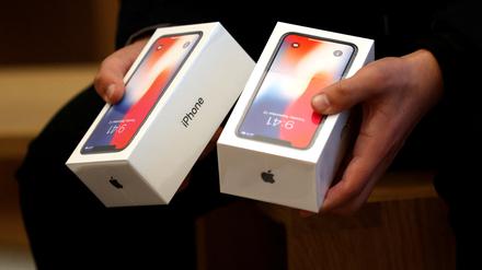 Ein Mann hält zwei Boxen für das iPhone X von Apple (Symbolbild).