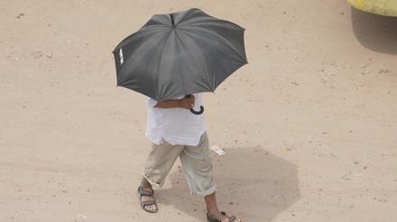 Bangladesch, Naogaon: Ein Mann schützt sich inmitten einer Hitzewelle mit einem Regenschirm vor Sonnenstrahlen.