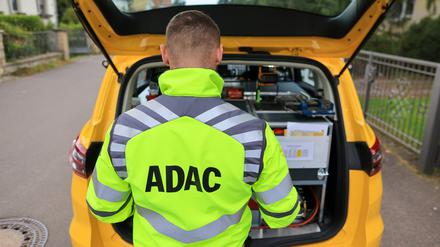 Ein ADAC-Pannenhelfer steht nach einer Pannenhilfe am Kofferraum seines Fahrzeugs (Symbolbild).