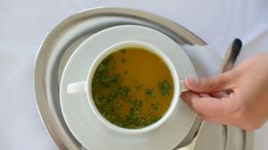 Eine Mitarbeiterin serviert am 01.07.2013 in der Buchinger-Wilhelmi-Klinik in Überlingen (Baden-Württemberg) für den Fotografen eine Tasse Suppe. Seit 60 Jahren kommen Menschen in die Buchinger Fastenklinik, um Gewicht zu verlieren oder innere Ruhe zu finden. Foto: Felix Kästle/dpa (zu dpa "Zwischen Fett und Fasten - die Suche nach dem gesunden Gewicht" vom 04.05.2015) +++(c) dpa - Bildfunk+++