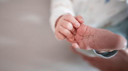 Ein Baby greift mit den Fingern nach seinem Fuß. (Symbolbild)