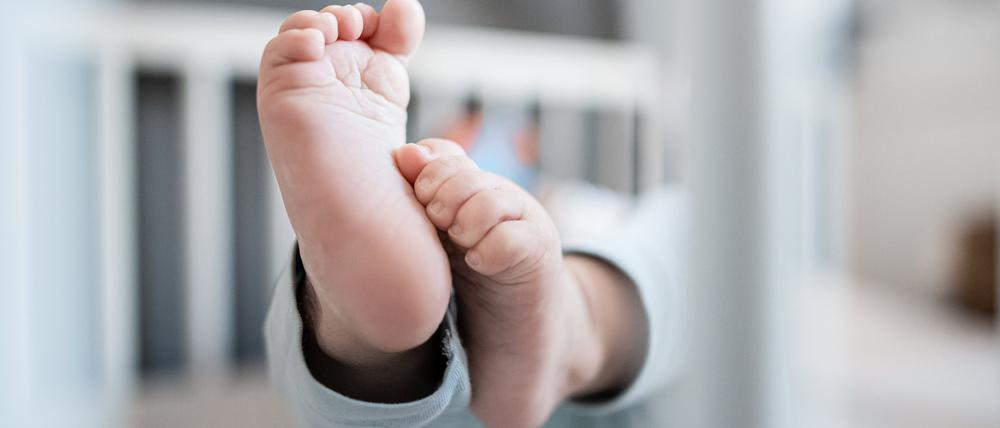 Die Füße eines Babys sind in einem Kinderbett zu sehen.