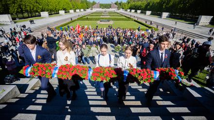 09.05.2023, Berlin: Ein Blumengesteck mit der russischen Flagge wird bei einer Gedenkveranstaltung die Treppen des Sowjetischen Ehrenmals im Treptower Park hinaufgetragen. Am 8. und 9. Mai jährt sich die Befreiung vom Nationalsozialismus zum 78. Mal. Foto: Christoph Soeder/dpa +++ dpa-Bildfunk +++