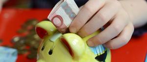 Ein fünfjähriger Junge steckt einen Zehn-Euro-Schein in sein Sparschwein, aufgenommen am 10.04.2012 in Berlin. 