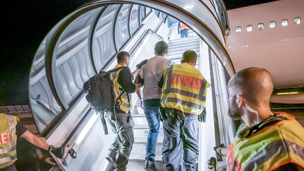 Polizeibeamte begleiten einen Menschen, der per Flugzeug in sein Heimatland zurückgebracht wird. 