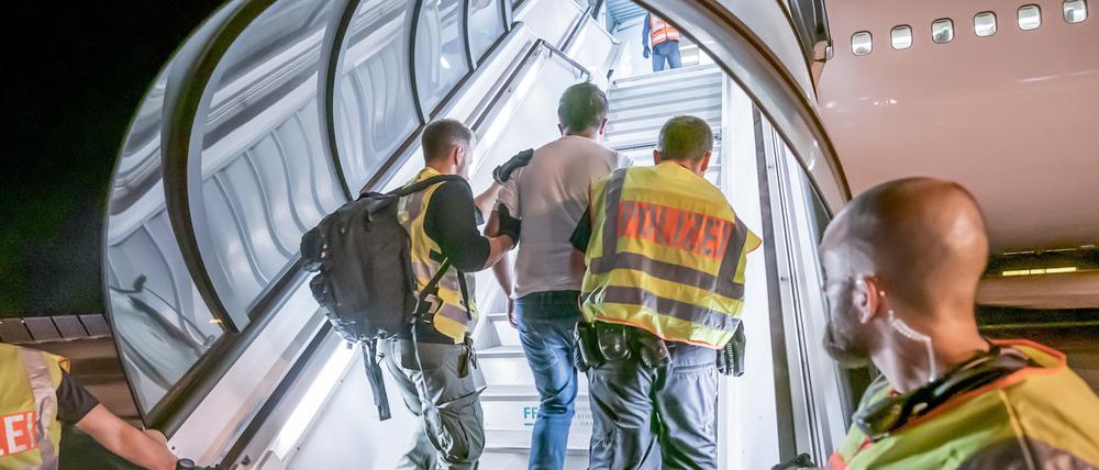 Polizeibeamte begleiten einen Menschen, der per Flugzeug in sein Heimatland zurückgebracht wird. 