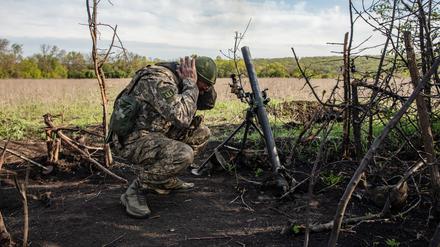 Ein Soldat einer Mörser-Einheit der ukrainischen Streitkräfte hält sich die Ohren zu.