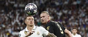Toni Kroos (l.) zeigt sich zufrieden mit dem Unentschieden gegen Manchester City und Stürmerstar Erling Haaland.