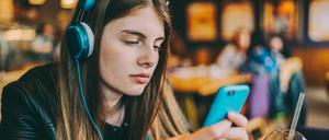 Young girl with headphones at cafeteria listening podcast